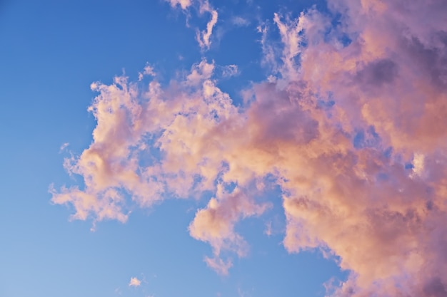 Nuvole rosa e gialle di colore pastello su cielo blu alla luce del tramonto