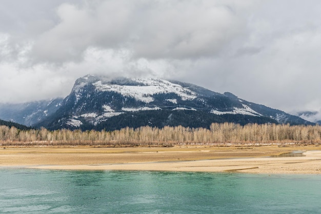 Nuvoloso giorno luminoso al fiume Columbia vicino a Revelstoke British Columbia grandi montagne sullo sfondo