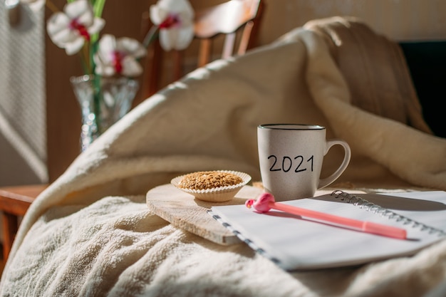 obiettivi risoluzione del nuovo anno iniziare a pianificare la tazza con il testo e aprire la penna del blocco note sul letto alla luce del sole tazza