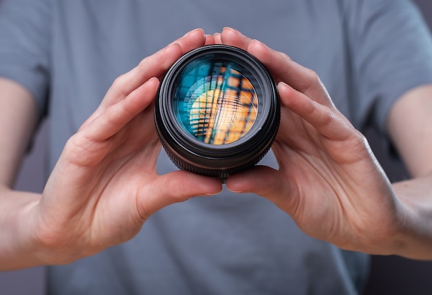 Obiettivo della fotocamera digitale con un bellissimo softbox da studio che riflette nelle mani della fotografa.