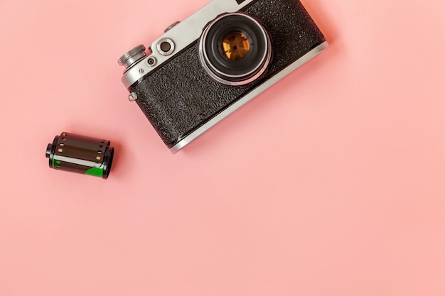 Obiettivo della macchina fotografica della foto della pellicola dell'annata e rotolo di pellicola sul tavolo rosa