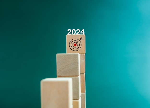 Obiettivo e successo 2024 anni di calendario numero sull'icona di destinazione in cima ai blocchi di legno del cubo di passaggi del grafico a barre Processo di crescita aziendale sviluppo leadership marketing concetti di miglioramento economico