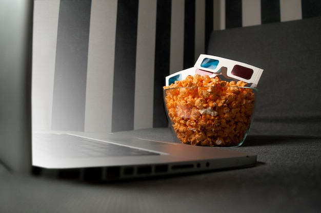 Occhiali 3D, popcorn e un computer portatile sono sdraiati sul divano nella stanza di notte