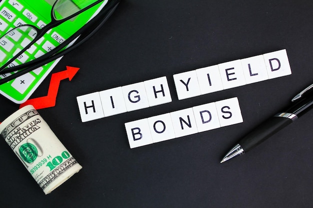 occhiali da calcolatore e carta moneta con la parola alfabeto HighYield Bonds