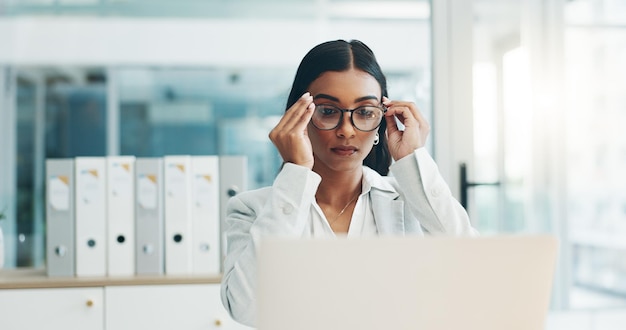 Occhiali da donna d'affari e lavoro sul laptop in ufficio per pianificare la lettura di e-mail e ricerche su Internet nello studio legale Avvocato avvocato indiano e concentrarsi sul computer per avviare l'analisi legale in azienda