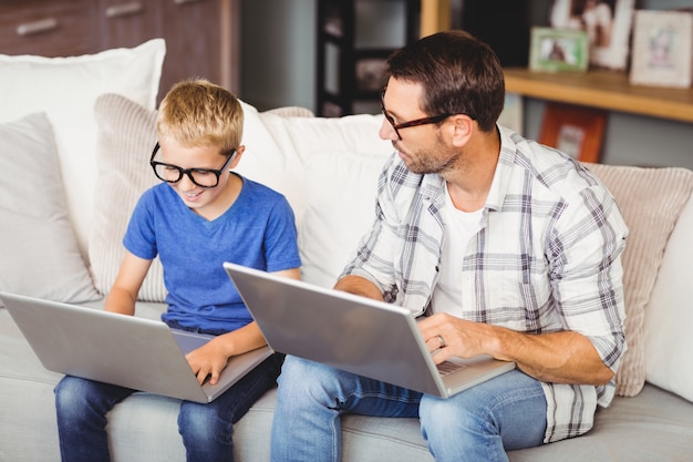 Occhiali da portare del figlio e del padre mentre lavorando al computer portatile