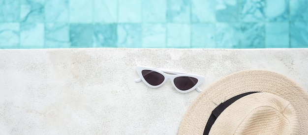 Occhiali da sole bianchi e cappello vicino alla piscina in un hotel di lusso Vacanze estive e concetto di fine settimana