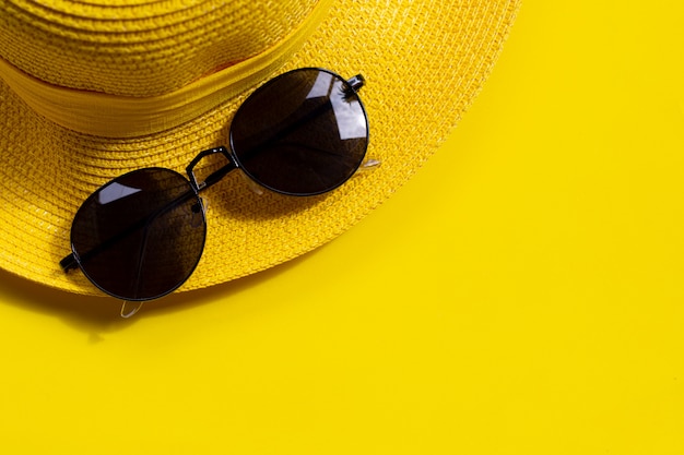 Occhiali da sole con cappello estivo su sfondo giallo. Goditi il concetto di vacanza.