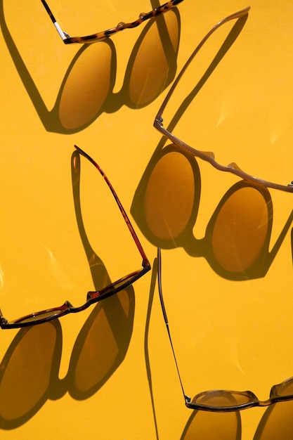 Occhiali da sole con una lunga ombra su un luminoso sfondo giallo estivo