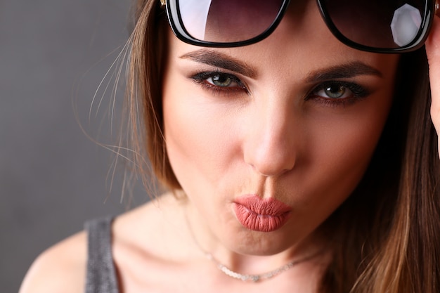 Occhiali da sole da portare sorridenti della bella giovane donna del brunette