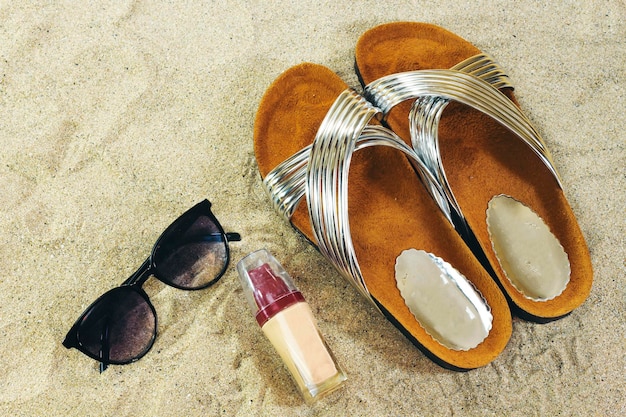 Occhiali da sole e pantofole con base liquida sul concetto di estate sulla sabbia