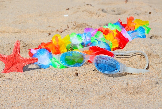 Occhiali da spiaggia e collana hawaiana su una costa dorata