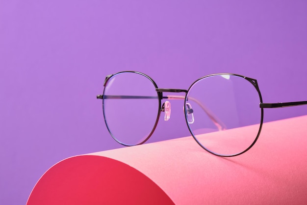 Occhiali da vista su sfondo geometrico rosa e viola, montature per occhiali alla moda copia spazio
