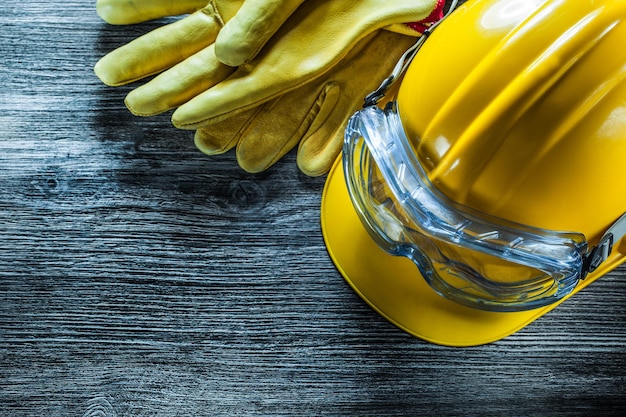 Occhiali di sicurezza guanti in pelle casco da costruzione su tavola di legno vintage