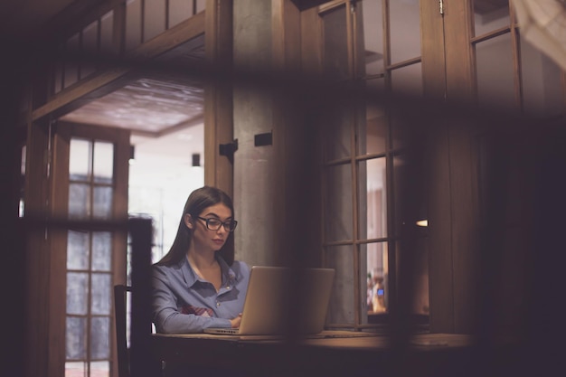 Occhiali è sulla donna La donna sta lavorando con il computer portatile grigio