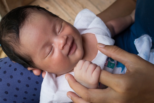 Occhio di sonno sveglio del bambino appena nato e sorriso sul ginocchio della madre