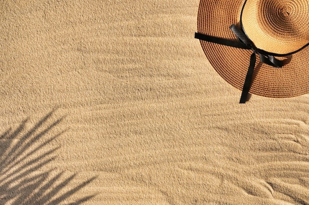 Oceano o mare, cappello di vimini sdraiato sulla sabbia, ombra di foglia di palma accanto all'impronta. Foto di alta qualità