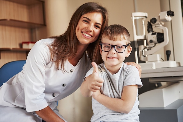 Oculista femminile seduto con il bambino dopo aver fatto il test di visione.