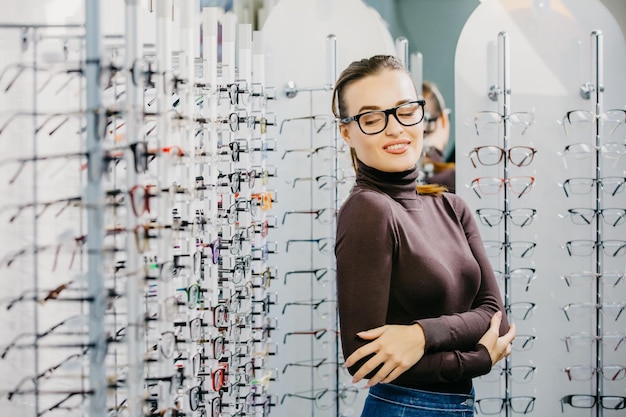 Oftalmologia La giovane donna sta scegliendo un occhiali nel negozio di ottica Correzione della vista