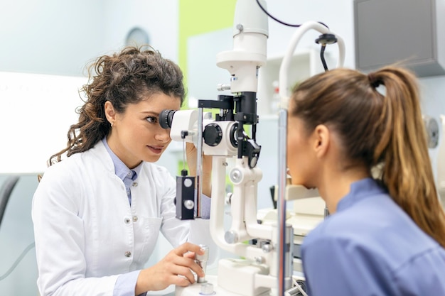 Oftalmologo con paziente femminile durante un esame in una clinica moderna Oftalmologista utilizza attrezzature mediche speciali per salvare e migliorare la salute degli occhi