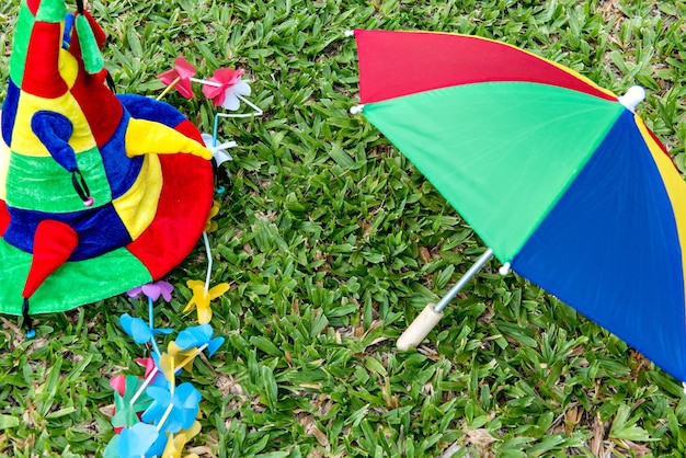 Oggetti di carnevale brasiliano che si trovano sull'ombrello e sulla collana variopinti del cappello dell'erba