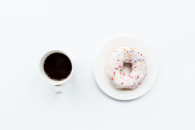 Oggetti piatti laici: tazza di caffè e ciambella sdraiato su sfondo bianco