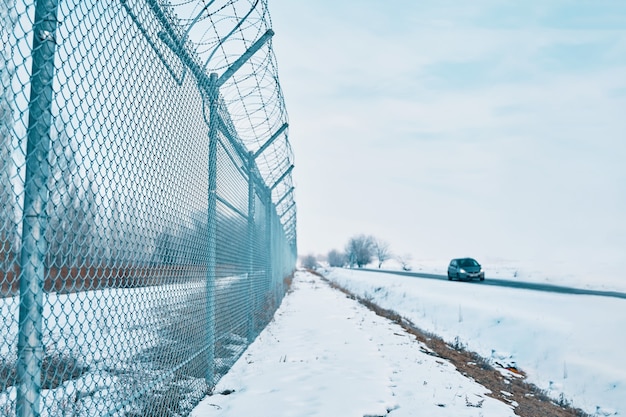 Oggetto privato protetto vicino al recinto di filo spinato dell'autostrada sul confine in chiusura invernale per quarantena una...