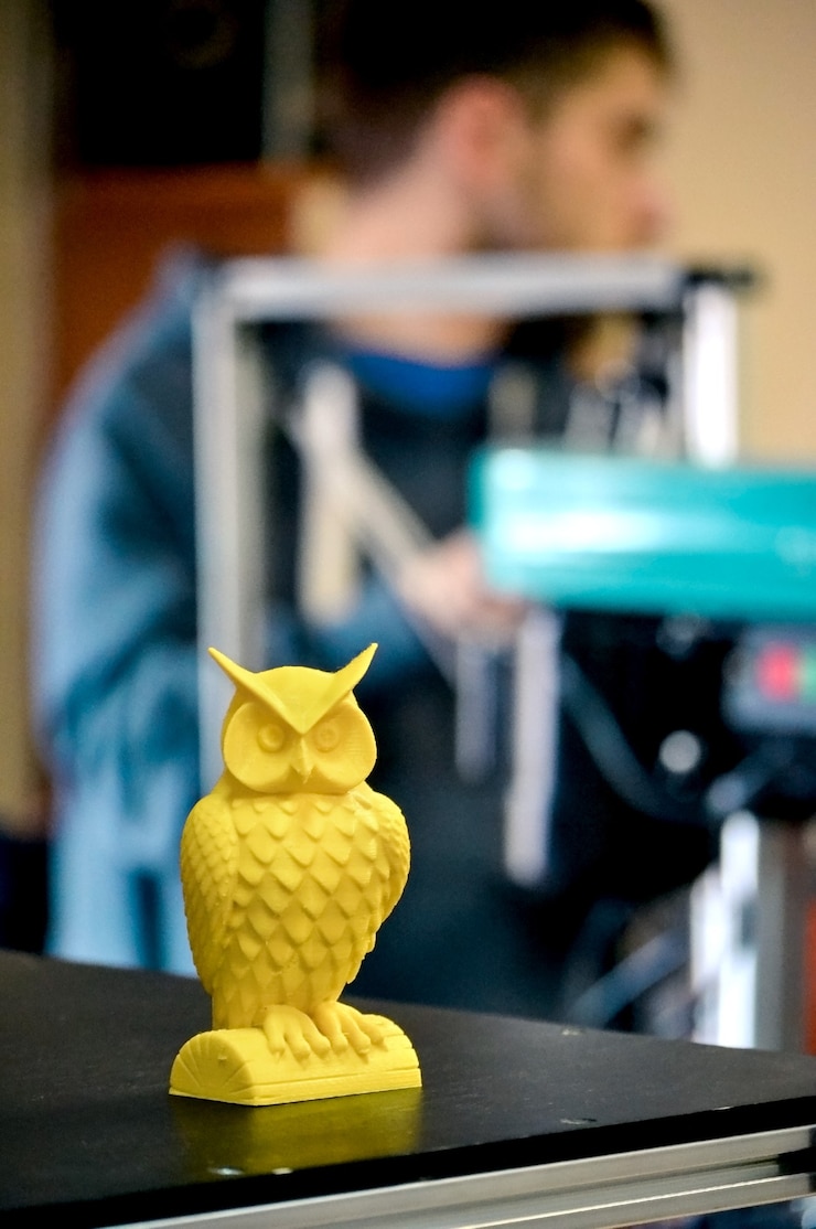 Foto oggetto stampato su un primo piano della stampante 3d in officina. la stampante 3d tridimensionale automatica esegue la modellazione di colori gialli in plastica in laboratorio. tecnologia additiva moderna e progressiva