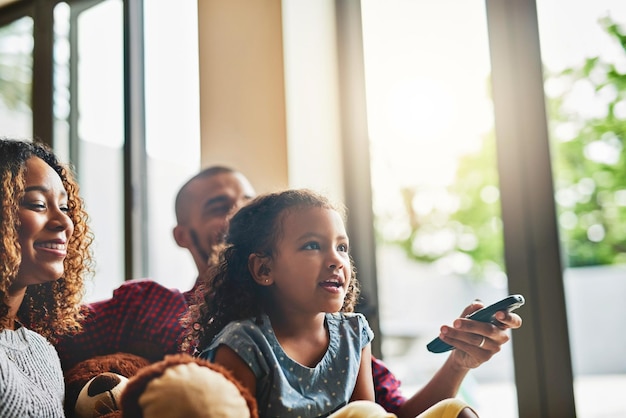 Ogni famiglia ha il suo programma televisivo preferito Foto di una giovane famiglia felice di tre persone che guarda la tv dal divano di casa