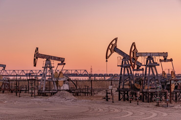 Oil Pumpjack against a sunset sky on background. industrial equipment. Rocking machines for power genertion. Extraction of oil. War on oil prices. Global coronavirus COVID 19 crisis.