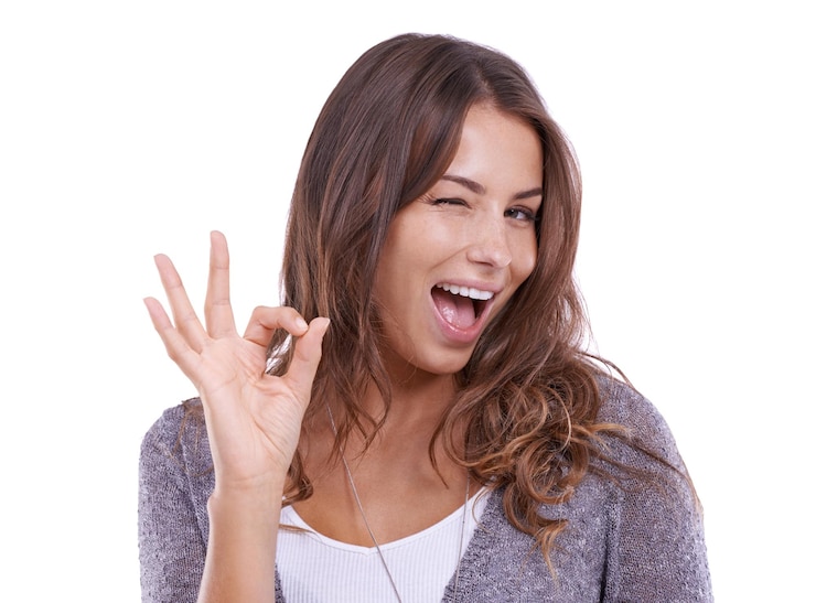 Foto ok occhiolino e ritratto di donna in studio per il voto notizie certificate e feedback su sfondo bianco modello felice lampeggiare con la mano emoji per il successo accordo e icona di eccellenza revisione e supporto