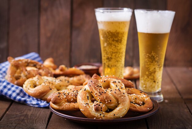 Oktoberfest ha salato le pretzelle morbide in una ciotola e birra dalla Germania sullo sfondo di legno.