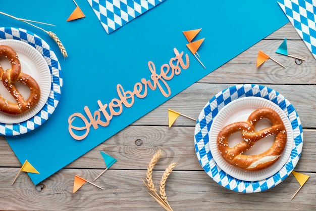 Oktoberfest rustico con prezels in piatti di carta, bandiere di carta e foglie di autunno