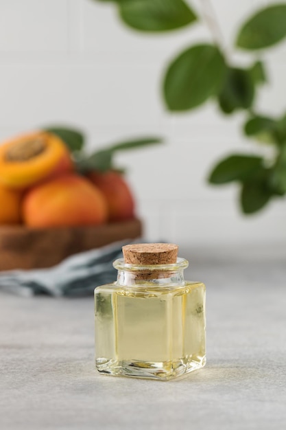 Olio con estratto di noccioli di albicocca primo piano sullo sfondo un piatto di legno con albicocche mature Aromaterapia