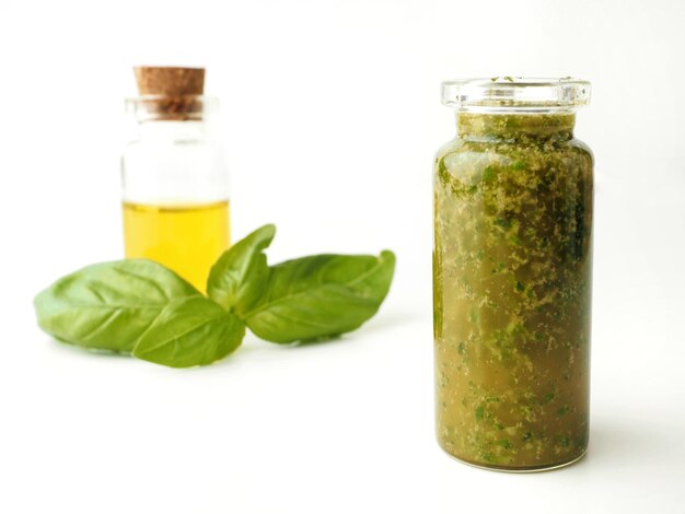 Olio d'oliva al basilico fatto in casa in una bottiglia su sfondo bianco