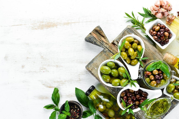 Olio d'oliva e olive su fondo di legno bianco Vista dall'alto Spazio libero per il testo