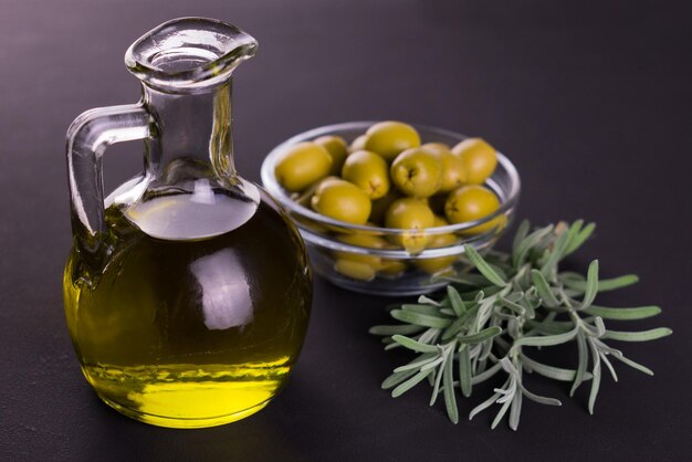 Olio d'oliva in bottiglia e rosmarino fresco su fondo scuro