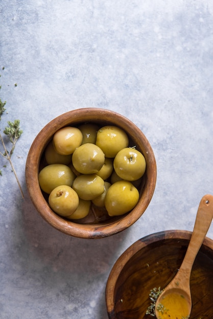 Olio d'oliva organico con le olive verdi in ciotola su fondo di pietra bianco con lo spazio della copia, alimento sano.