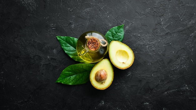 Olio di avocado e avocado freschi su sfondo nero Stile rustico Vista dall'alto Spazio libero per il testo