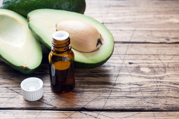 Olio di avocado e avocado su fondo di legno con lo spazio della copia.