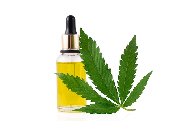 Olio di cannabis in bottiglia trasparente e foglia di cannabis su uno sfondo bianco isolato.