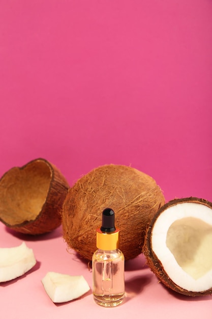 Olio di cocco con cocco su sfondo rosa. Foto verticale
