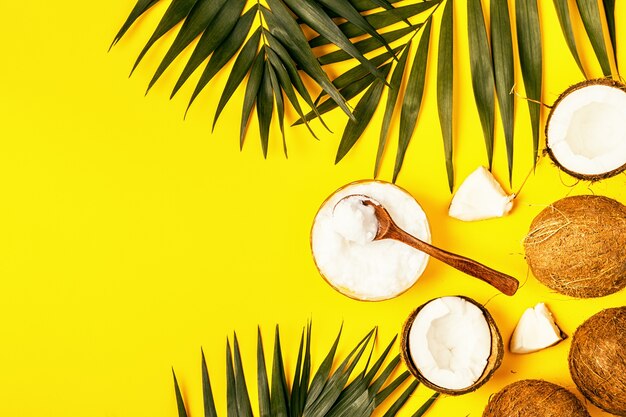 Olio di cocco e noci di cocco su uno sfondo con foglie tropicali