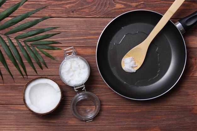 Olio di cocco e una padella su un primo piano della tavola di legno