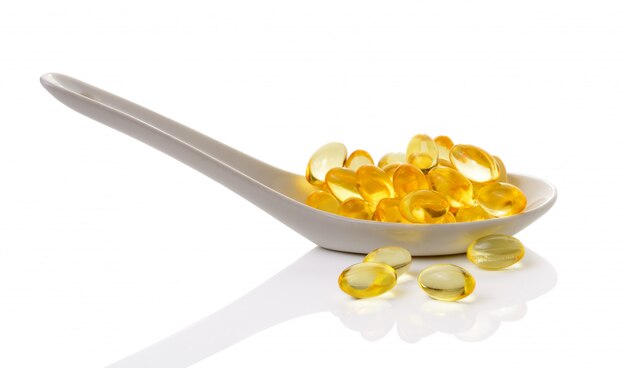 Olio di fegato di merluzzo Omega 3 capsule di gel in cucchiaio su spazio bianco