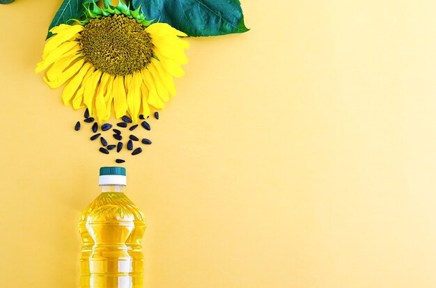 Olio di girasole con fiore giallo e semi in bottiglia.