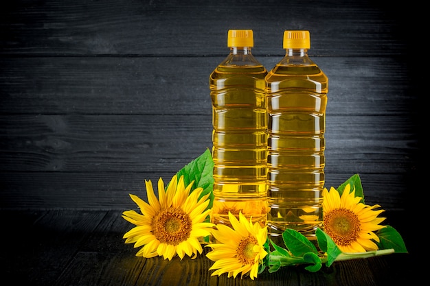 Olio di girasole con fiori su fondo rustico nero