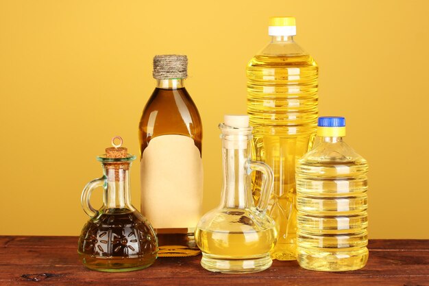 Olio di oliva e di girasole in bottiglie e piccoli decanter su sfondo giallo