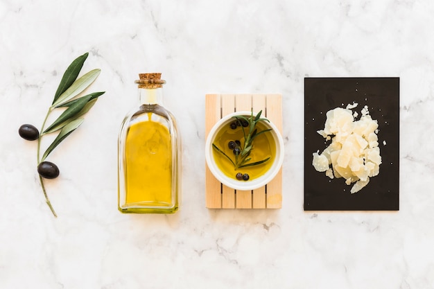 Olio di oliva e pepe nero in ciotola e bottiglia con formaggio su sfondo di marmo bianco