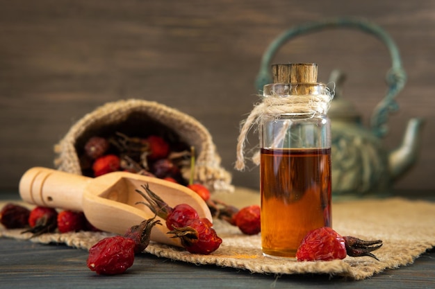 Olio di rosa canina su fondo di legno con frutti rossi